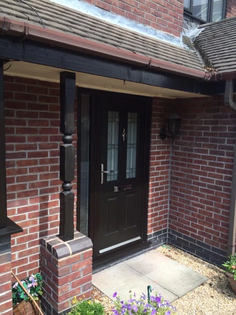 Black composite front door with sidelight under porch