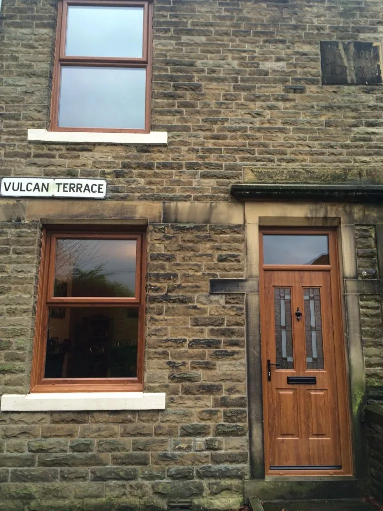 Golden oak composite door and matching uPVC windows on stone terrace