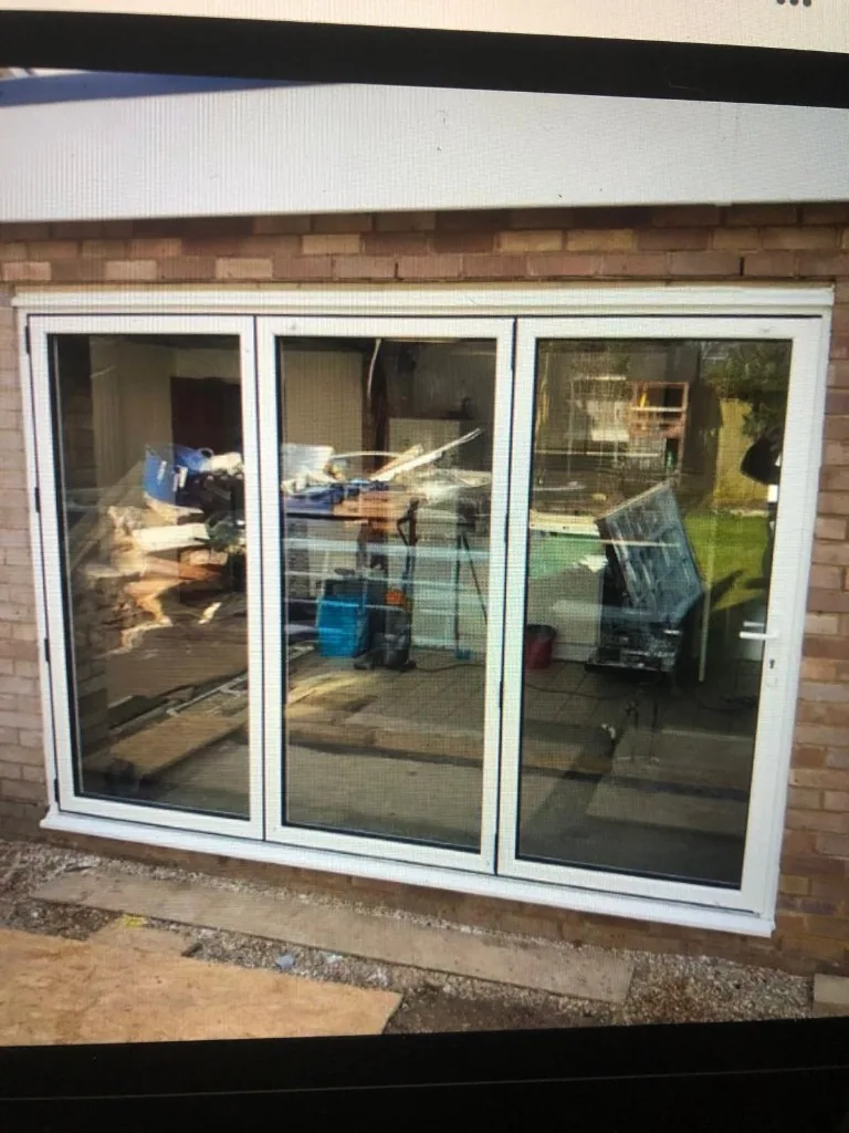 White three pane bi-fold doors in brick wall